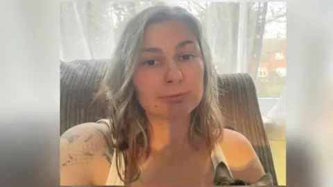 Lauren Buckland A woman wearing a white tank top smiling at the camera. 
