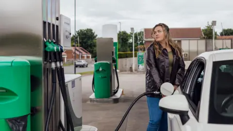 Getty Images A young woman fills up her car at a petrol station