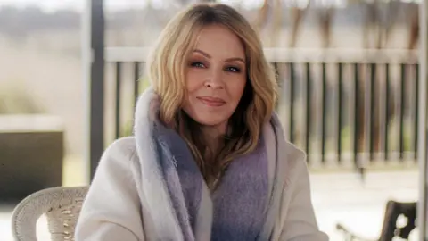 PA/Netflix Kylie Minogue smiling at the camera while wearing a fur coat in the new three-part Netflix documentary, Kylie