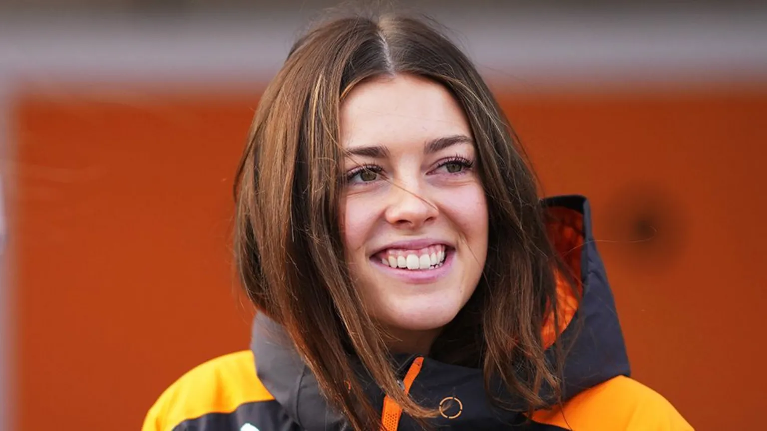 Getty Images Ella Stevens smiling while wearing a black and orange raincoat.