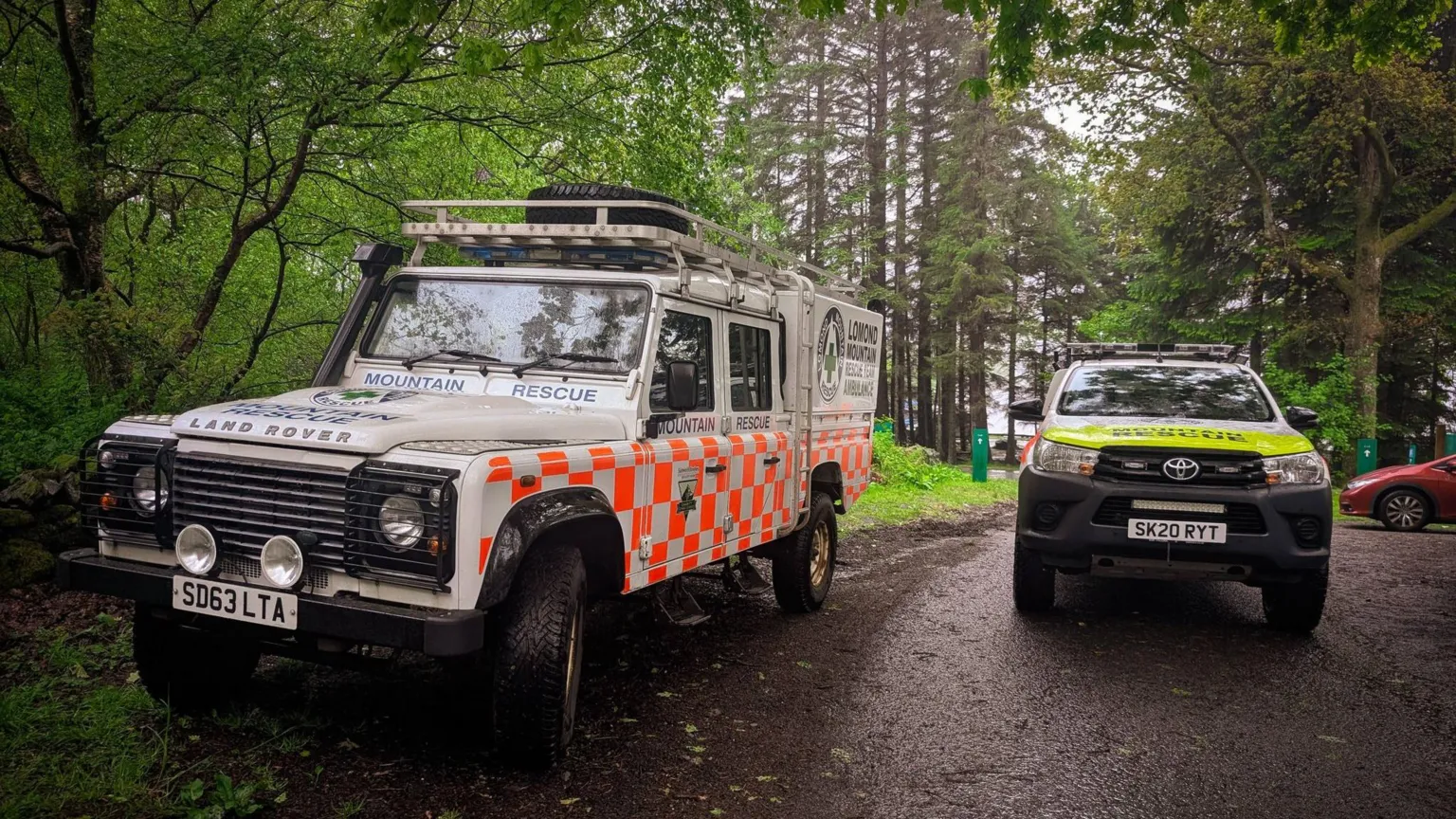 LOMOND MRT An image of two offroad vehicles in the Lomond Mountain Rescue livery parked up on a woodland path on the West Highland Way. 