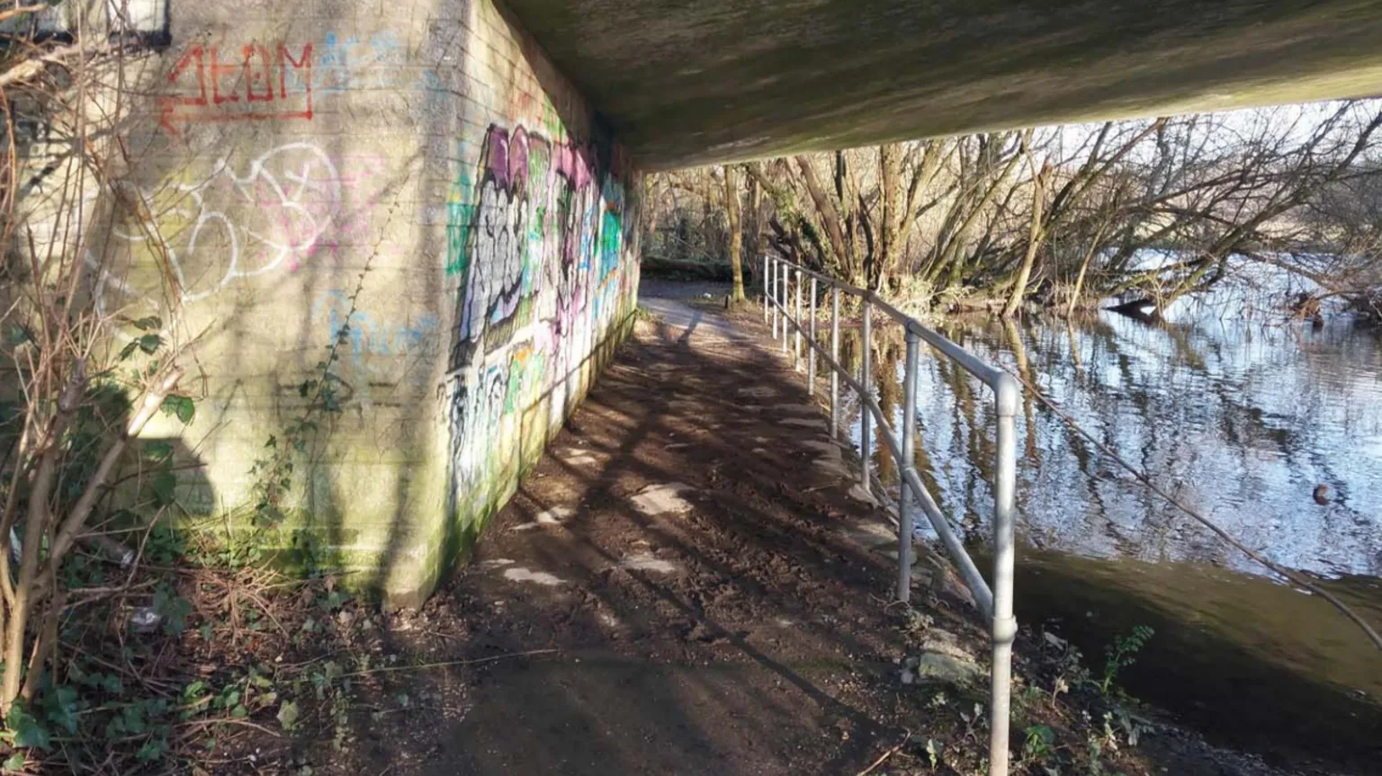 Crown Prosecution Service A footpath beside a river, leading under a road bridge
