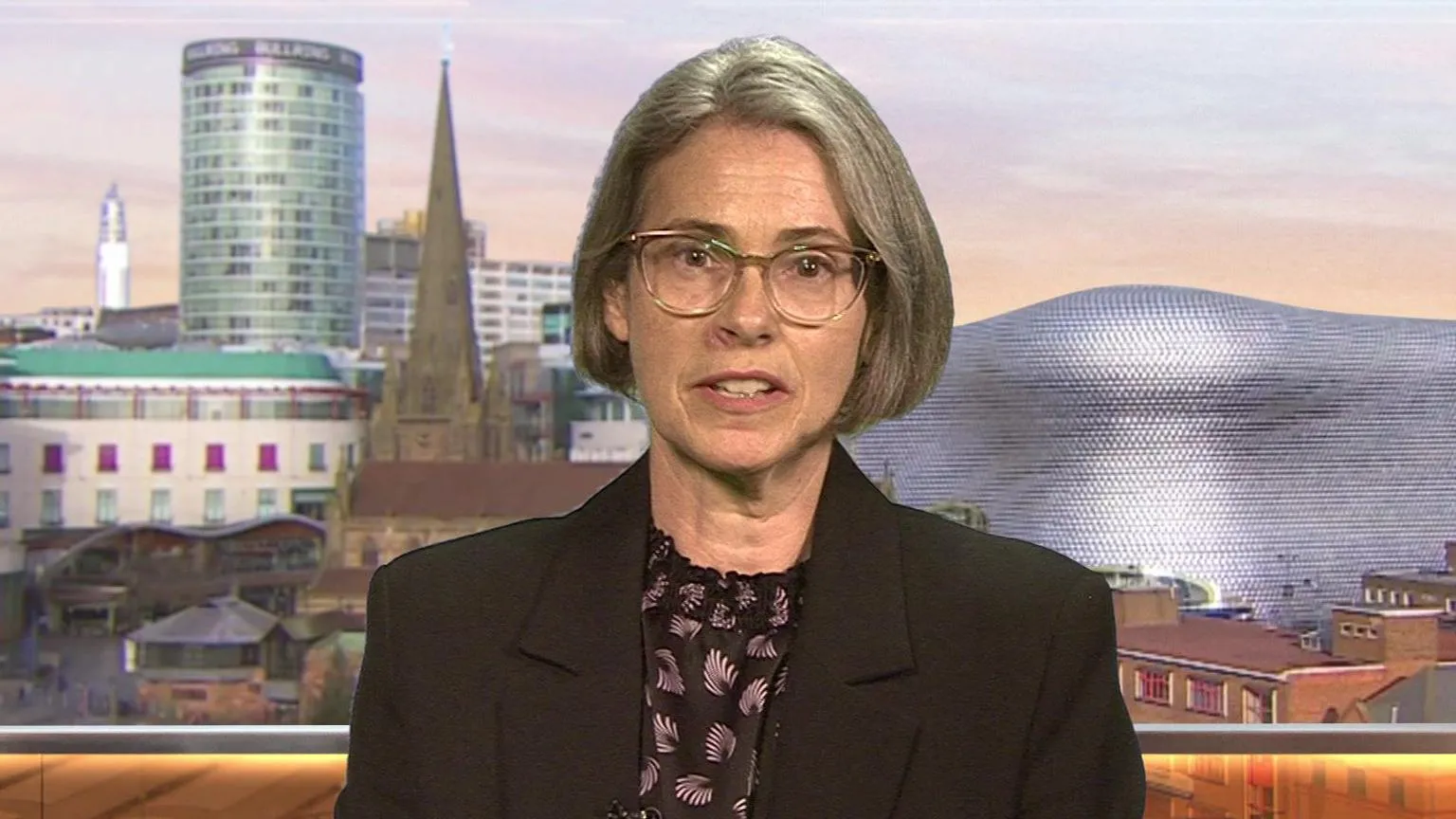 Siobhan Blake gives an interview in a BBC studio. She has a grey bob and glasses and wears a dark jacket over a blouse.