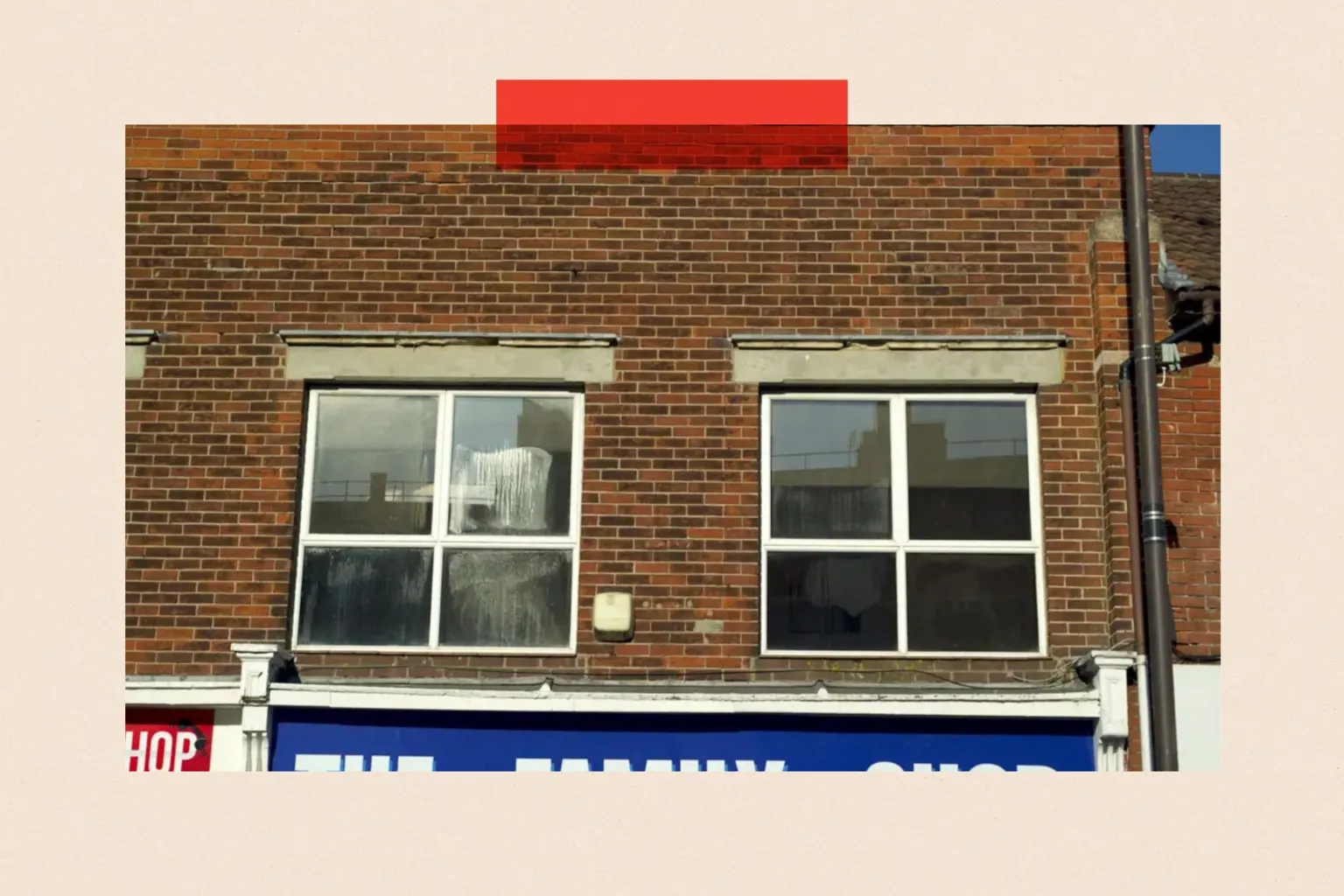 Exterior photograph of a red-brick building with two windows above a commercial property